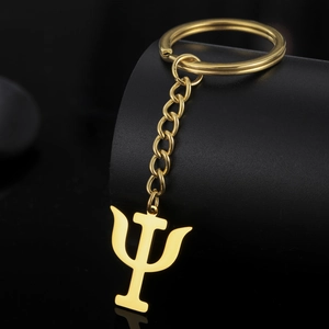 Macro shot of a polished golden stainless steel Psi symbol keychain on a black pedestal