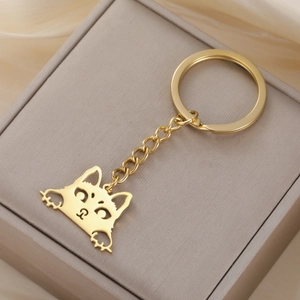 Macro shot of polished gold-finished stainless steel cat pendant keychain on silk fabric