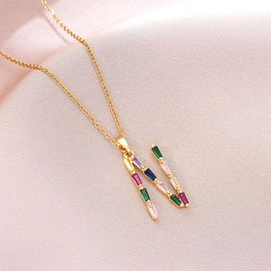 Détail du collier doré avec pendentif lettre N serti de cristaux multicolores