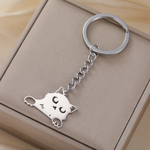Macro shot of polished stainless steel cartoon cat pendant on beige leather background