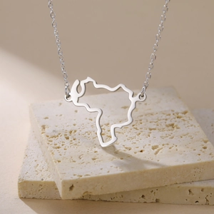 Polished silver hollow map pendant necklace on minimal textured stone display