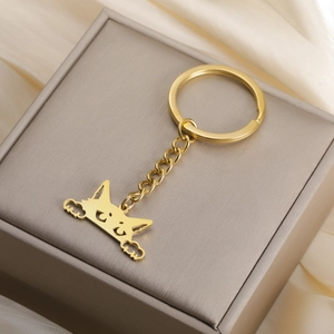 Detailed close-up of a cartoon cat pendant on a gold keychain over a luxury gift box