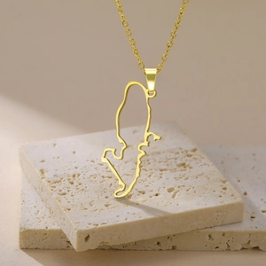 Detail of gold hollowed Sweden map pendant with fine link chain on stone surface