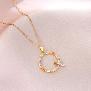 Macro d'un pendentif lettre Q orné de pierres précieuses colorées sur une chaîne dorée