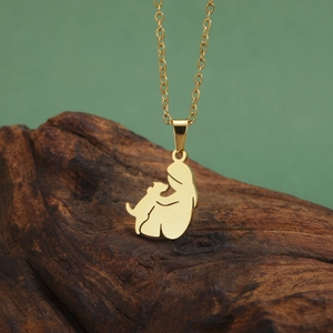 Polished gold stainless steel necklace featuring a girl hugging a dog pendant on wood