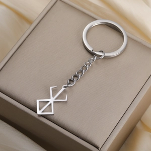 Close-up of a silver 304 stainless steel Berserk Brand of Sacrifice keychain on silk