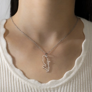 Close-up of a silver hollowed-out map pendant necklace worn by a female model on white