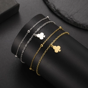 Detail of gold and silver clover pendant bracelets with beads on a black stand