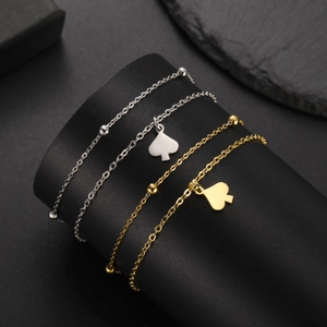 Polished gold and silver spade heart bracelets on black textured display stand