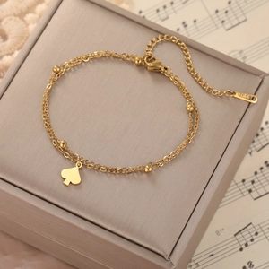 Close-up of golden double-layered stainless steel heart bracelet on vintage music score