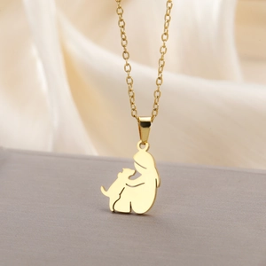 Detailed view of gold stainless steel silhouette pendant necklace on silk fabric