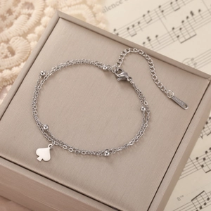 Detail of silver double-layer stainless steel bracelet with heart charm on jewelry box