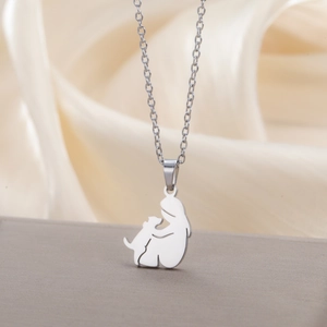 Close-up of minimalist stainless steel necklace with silhouette of a girl hugging a dog