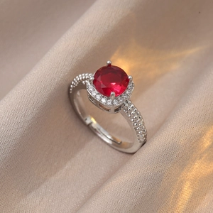 Détail d'une bague en argent avec pierre rouge et texture perlée sur soie champagne