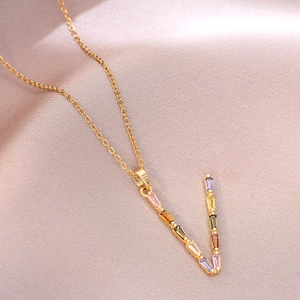 Détail du collier en acier titane doré avec pendentif en V et zircons colorés