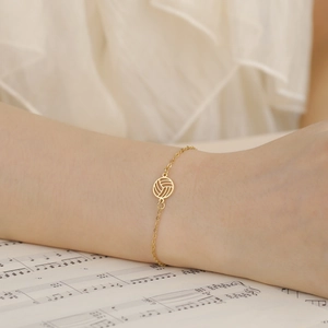 Detaillierte Nahaufnahme eines goldenen Volleyball-Armbands am Handgelenk einer Frau