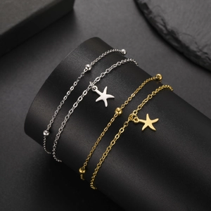 Detailed view of silver and gold stainless steel bracelets with starfish pendant and beads
