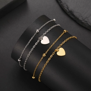 Polished stainless steel heart bracelets in gold and silver finish on a display