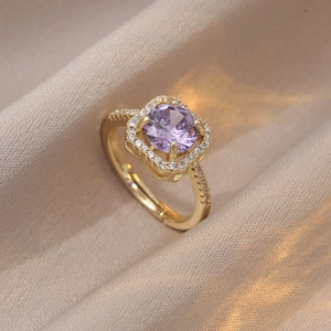 Vue macro d'une bague halo dorée avec un grand zircon violet et détails de pavé