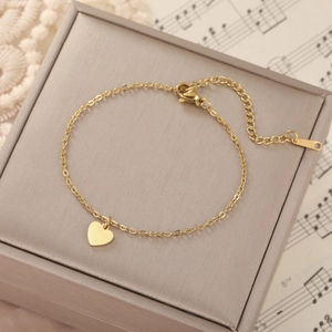 Detail shot of a golden heart pendant bracelet on a jewelry box with lace and music sheet