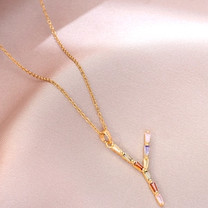 Gros plan du collier en acier titane doré avec pendentif lettre Y en gemmes colorées