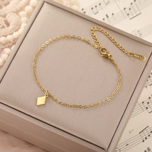 Polished 18K gold stainless steel bracelet with diamond charm on musical score background
