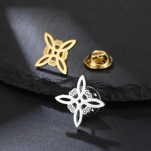 Macro detail of gold and silver Celtic witch knot brooches on black rock surface