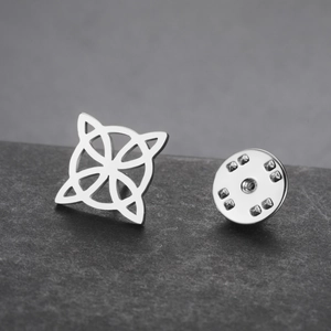 Macro shot of a silver Celtic knot lapel pin and butterfly clutch on dark stone