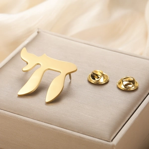Macro shot of gold-plated Chai symbol pin with metal butterfly clutches on silk