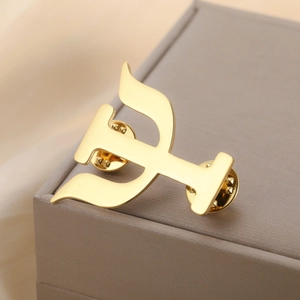 Detailed close-up of golden metal Psi symbol pin with dual butterfly clutch backing