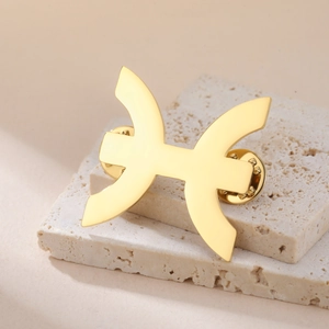 Detailed close-up of a gold-plated Pisces zodiac brooch with dual butterfly clutch backs