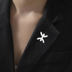Polished white Amazigh cultural symbol brooch pinned on a classic black suit jacket
