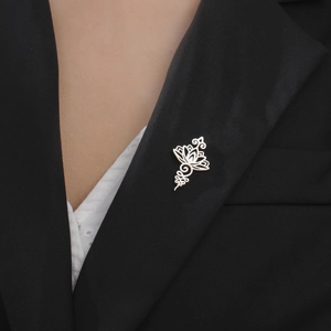 Detailed close-up of a silver lotus flower brooch pinned on a black suit lapel