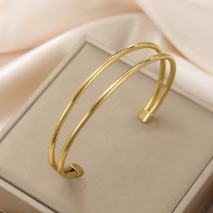 Primer plano del brazalete dorado de doble capa minimalista en una caja de joyería
