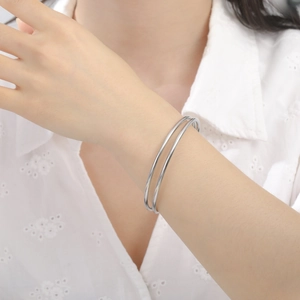Vista detallada de un brazalete minimalista plateado de doble capa en acero inoxidable