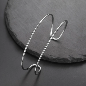Detalle de brazalete rígido de doble hilo en acero inoxidable pulido sobre plato de piedra