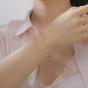 Vista macro detallada de un brazalete de doble capa en oro pulido en la muñeca femenina