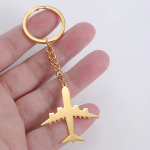 Golden stainless steel airplane keychain with matte finish held against white background