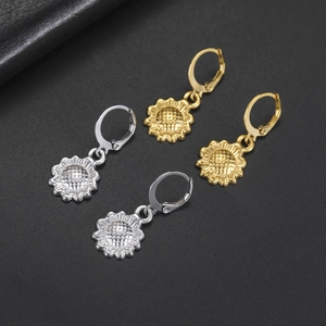 Dettaglio degli orecchini a girasole in oro e argento su sfondo scuro testurizzato