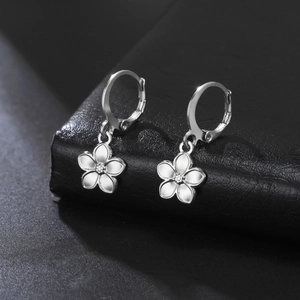 Dettaglio ravvicinato di orecchini a cerchio in argento con fiori in smalto bianco