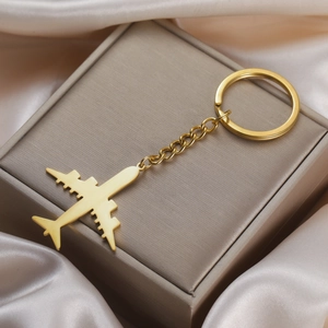 Polished gold airplane keychain with chain and ring on silk fabric luxury gift display