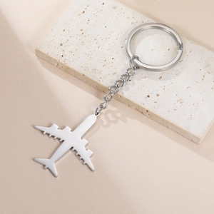 Detailed view of silver stainless steel airplane keychain on natural stone surface