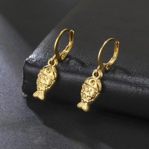 Macro shot of gold stainless steel fish pendant earrings on premium black leather