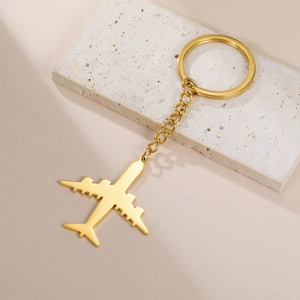 Polished gold aircraft keychain macro showing reflective metal airplane pendant on a chain