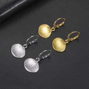 Detailed macro view of gold and silver seashell hoop earrings on a dark textured background