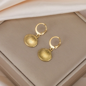 Macro detail of gold fan-shaped seashell earrings on a champagne silk jewelry gift box