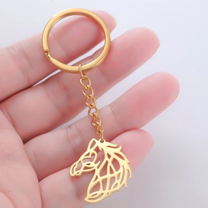 Polished gold hollow horse head keychain held in hand to show minimalist size and detail