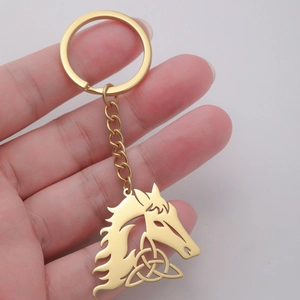 Golden stainless steel horse head keychain with Celtic knot detail held in hand