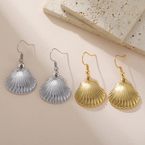 Detailed view of gold and silver scallop shell dangle earrings on natural stone background