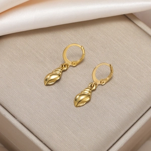 Detailed close-up of golden hoop earrings featuring intricate conch shell charms on satin